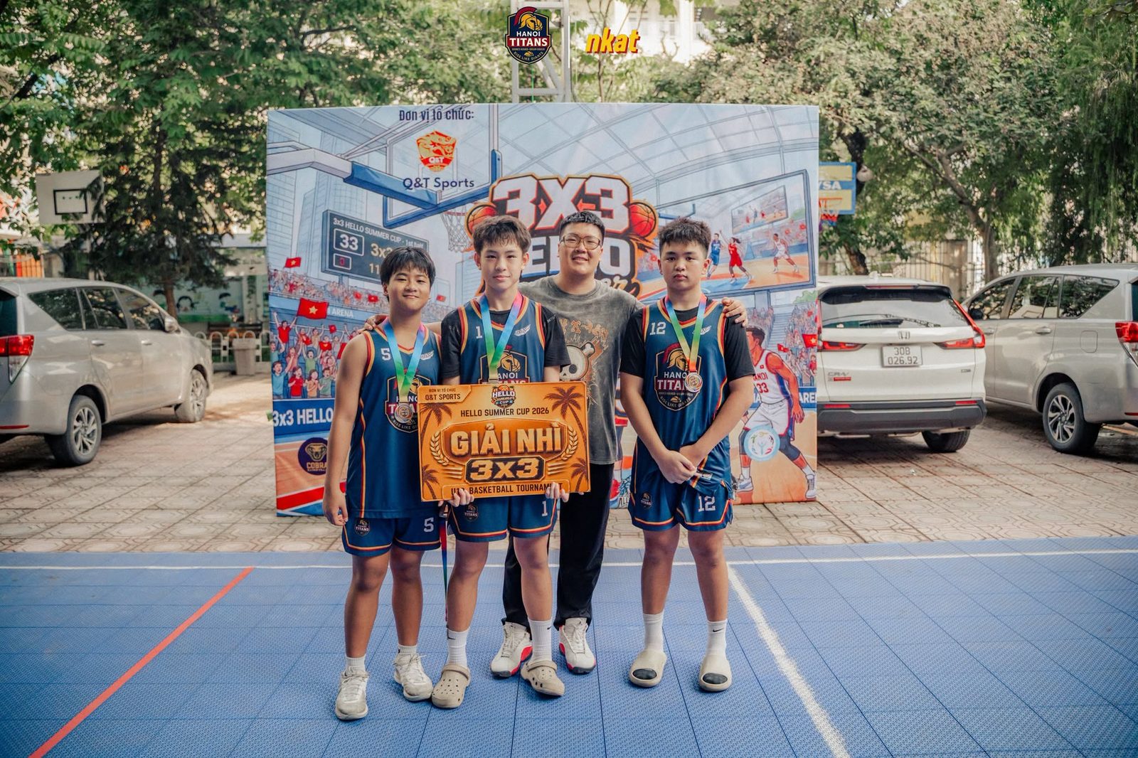 Ba cầu thủ Hanoi Titans đeo huy chương cầm băng rôn Giải Nhì 3x3 đứng cạnh một người lớn