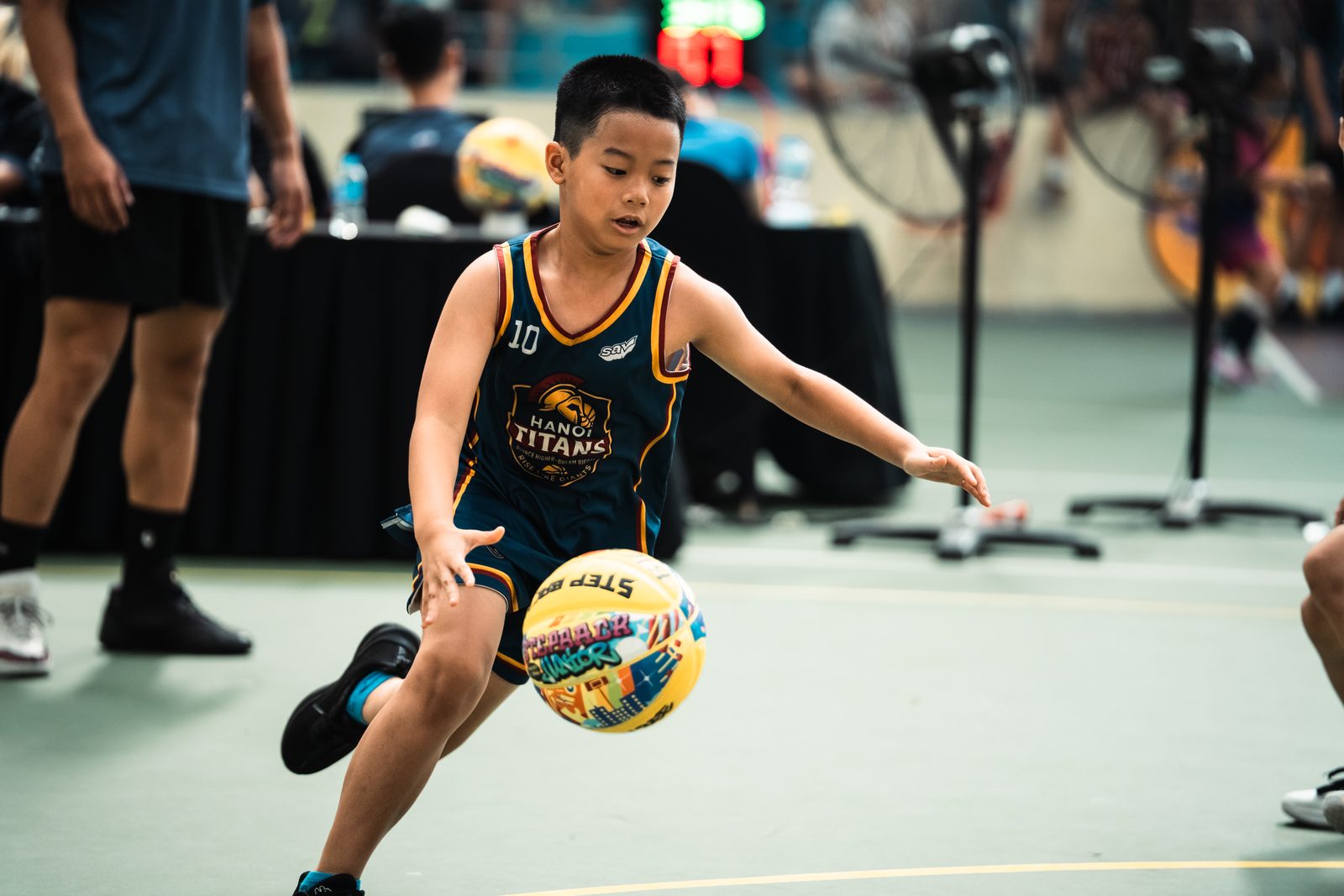Một cầu thủ nhí U9 Hanoi Titans cúi người dẫn bóng trên sân