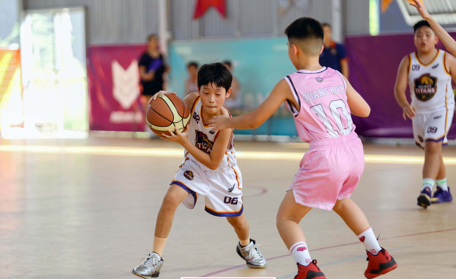 Cầu thủ nhí Hanoi Titans áo trắng ôm bóng đột phá trước cầu thủ đối phương áo hồng