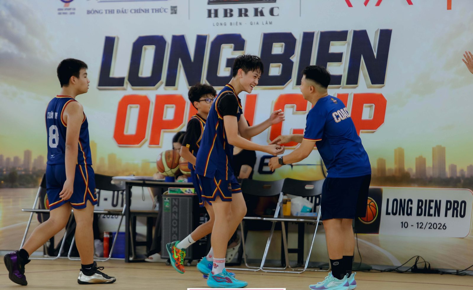 Các cầu thủ U13 Hanoi Titans áo xanh navy trao đổi với nhau trước phông Long Biên Open Cup
