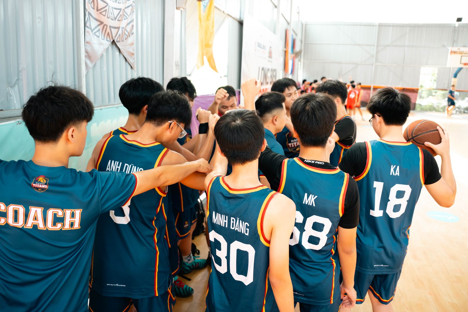 Các cầu thủ U15 Hanoi Titans chụm tay quanh huấn luyện viên trước giờ thi đấu
